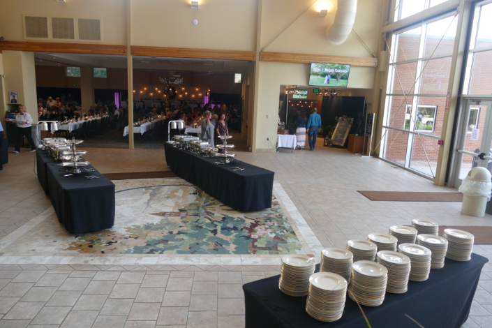 Buffet setup in the FACC atrium with chafers and stacked plates.