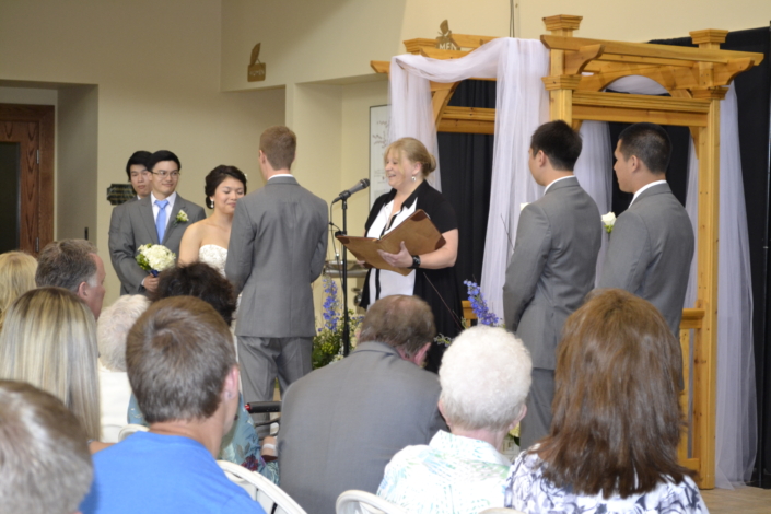 Atrium wedding ceremony with wooden arch and draped fabric.