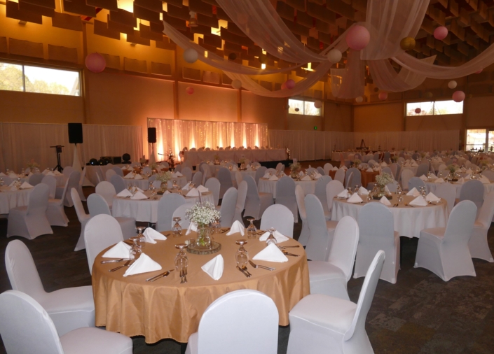 Full Expo Hall wedding setup with white chair covers and hanging lanterns.