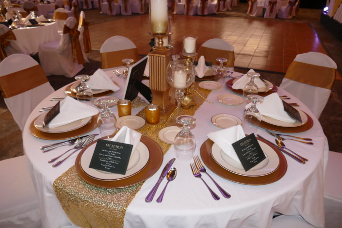 Gold and white wedding table setup with candles and elegant decor.