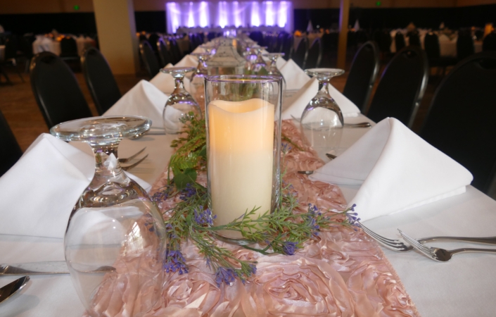 Long reception table with candle and floral runner centerpiece.