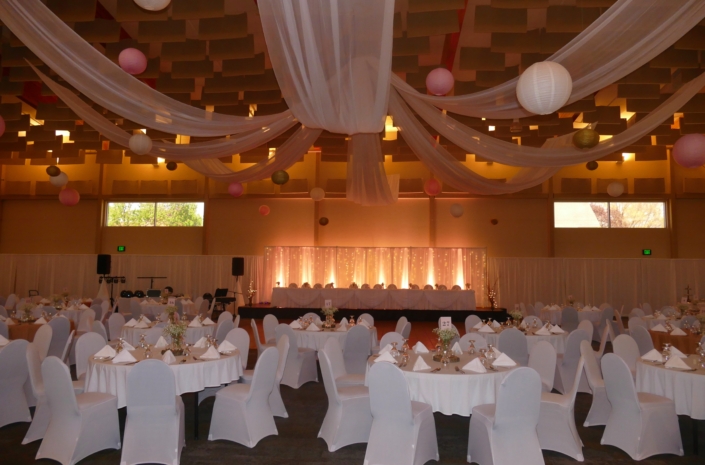 Wedding head table with draped ceiling fabric and lanterns.
