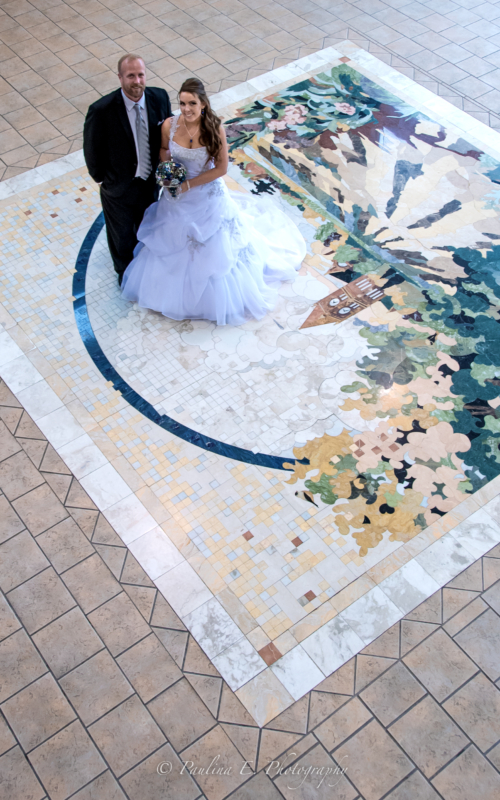 Bride and groom standing on the mosaic floor in the Atrium at the Fairfield Arts & Convention Center in Fairfield, Iowa.