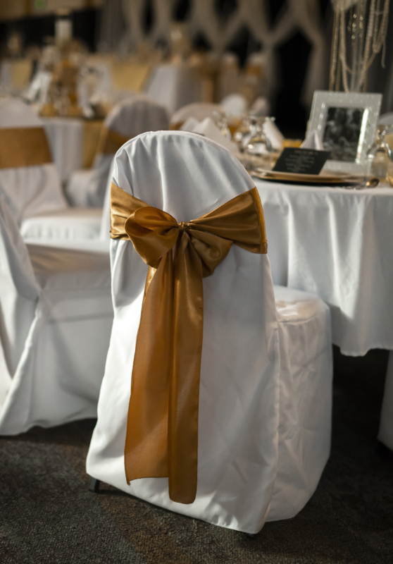 Wedding reception chair with a white cover and gold sash at the Fairfield Arts & Convention Center in Fairfield, Iowa.