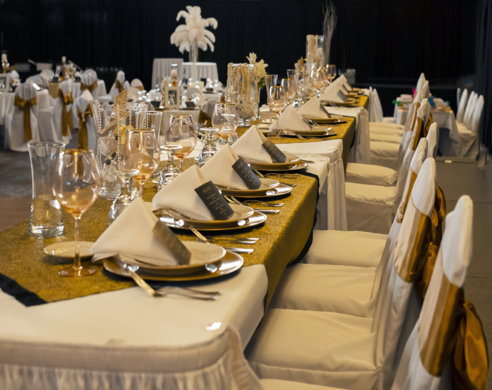 Wedding head table decorated with gold accents, white linens, and elegant place settings at the Fairfield Arts & Convention Center in Fairfield, Iowa.