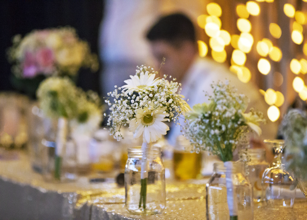 Daisy and baby’s breath wedding centerpieces in mason jars on a reception table at the Fairfield Arts & Convention Center in Fairfield, Iowa.